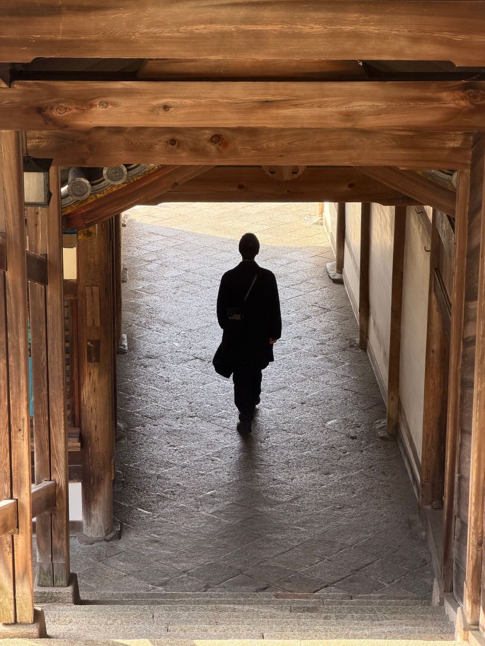 Buddhist monk in traditional robes preparing matcha tea in a simple wooden temple room with natural morning light.