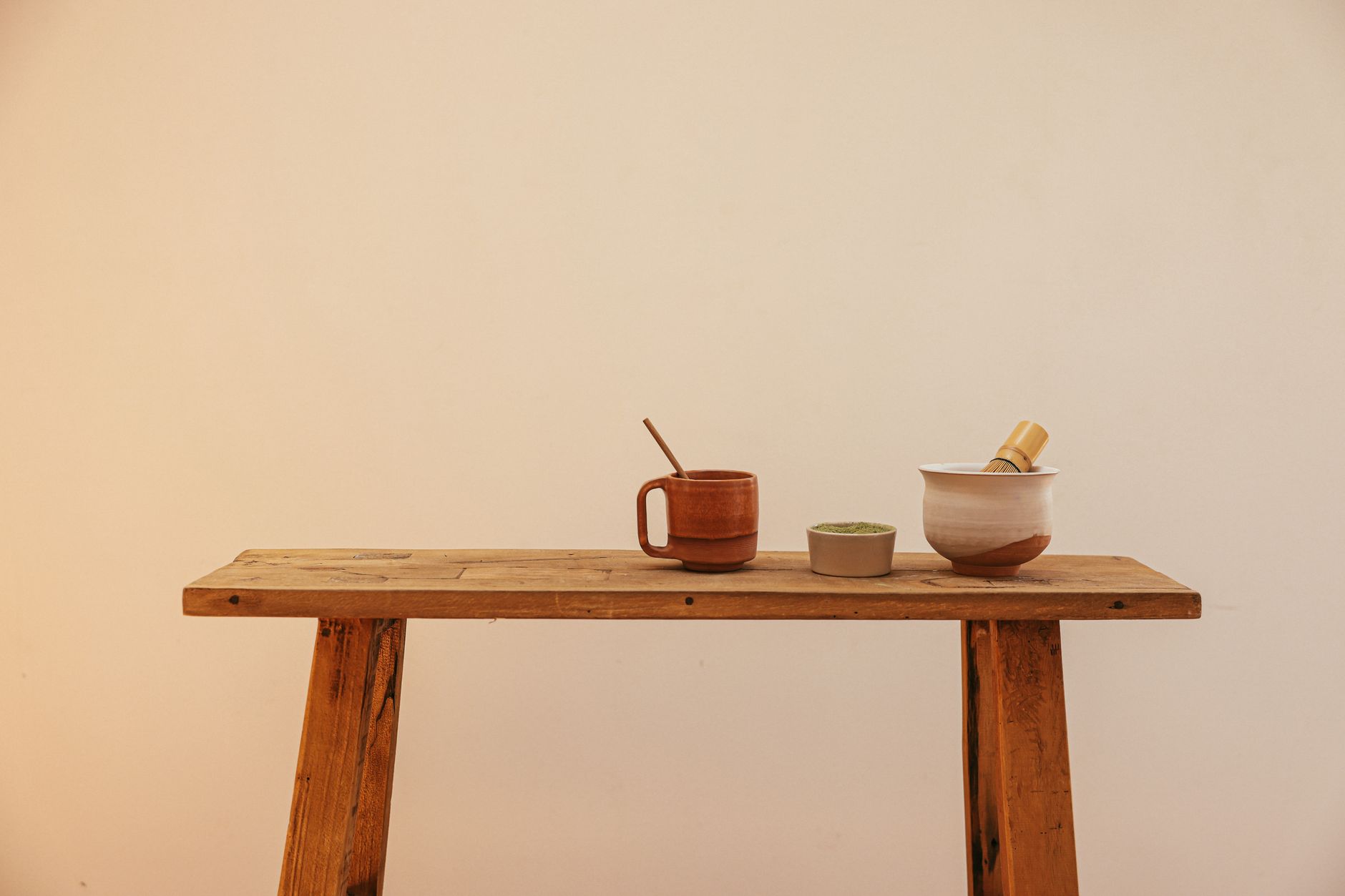 Vibrant green matcha powder in a ceramic bowl beside a bamboo whisk on a traditional Japanese tea mat.