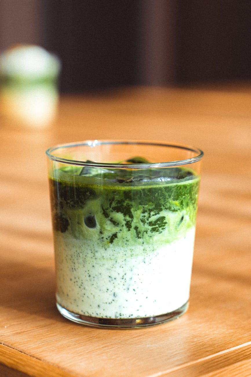 Vibrant green matcha powder in a ceramic bowl beside a bamboo whisk on a traditional Japanese tea mat.