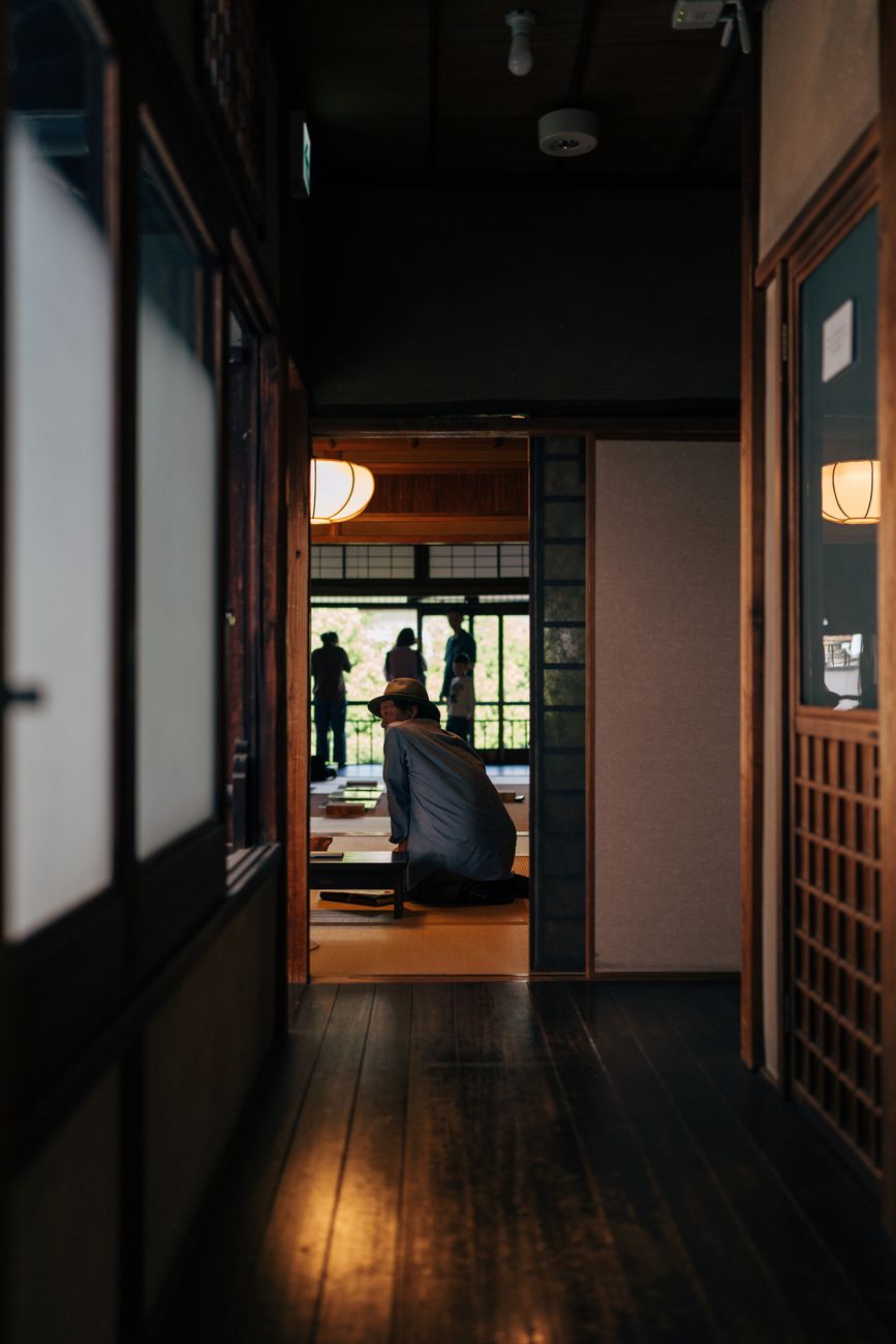 Samurai warrior in traditional hakama kneeling before a simple tea bowl in a minimalist tatami room during ceremony.