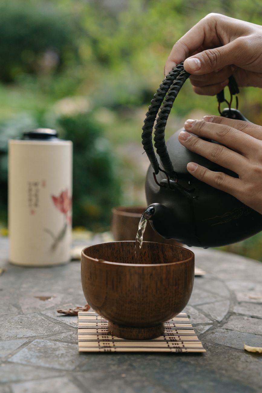 Two Japanese tea cups on bamboo mat showing bright green gyokuro and lighter sencha leaves side by side