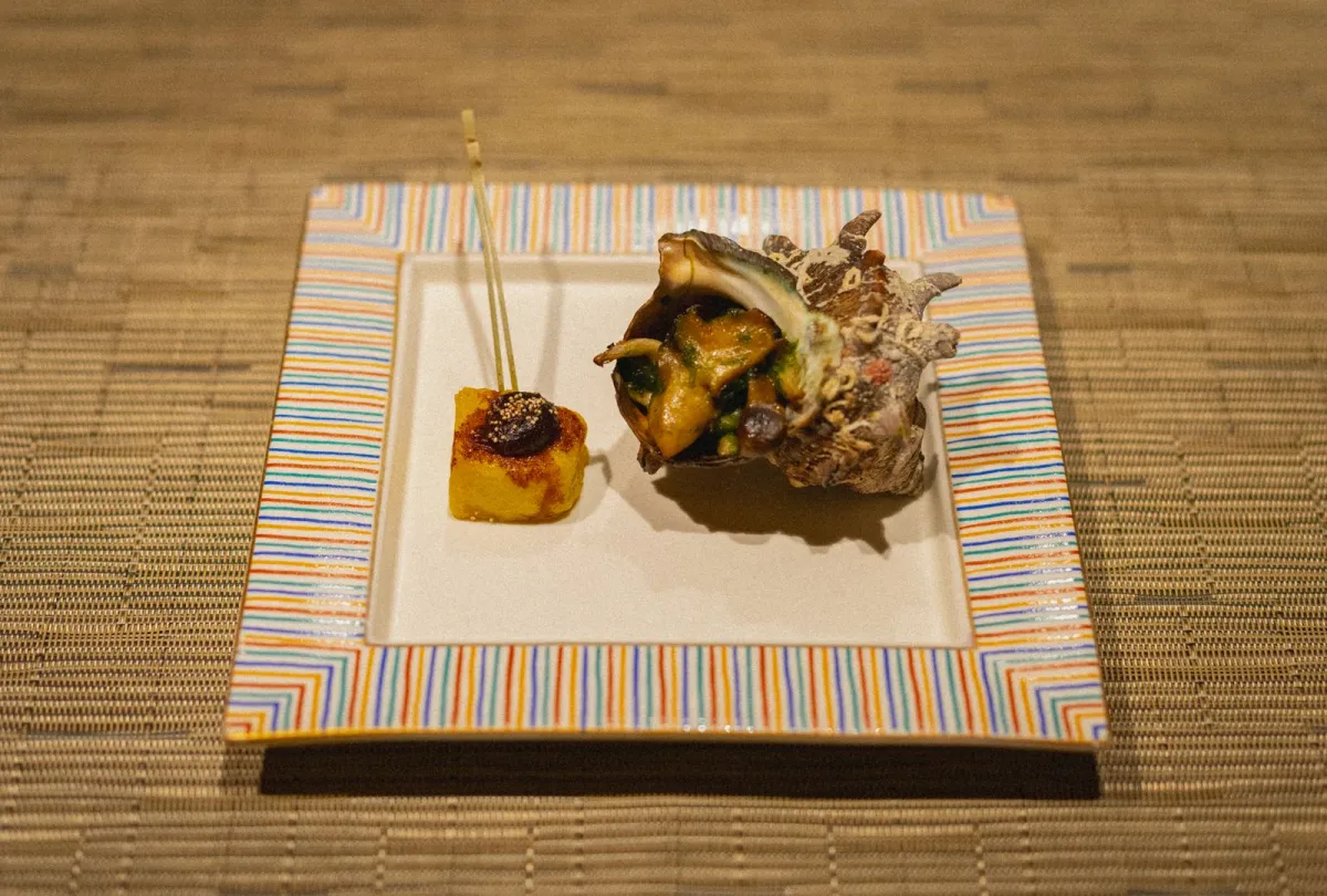 A Japanese dish arranged with empty space, varied height and seasonal garnish on a ceramic plate