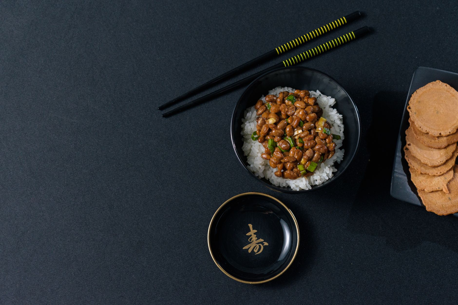 Traditional Japanese meal setting showing rice bowl on the left, miso soup on the right, with chopsticks and side dishes arranged properly.