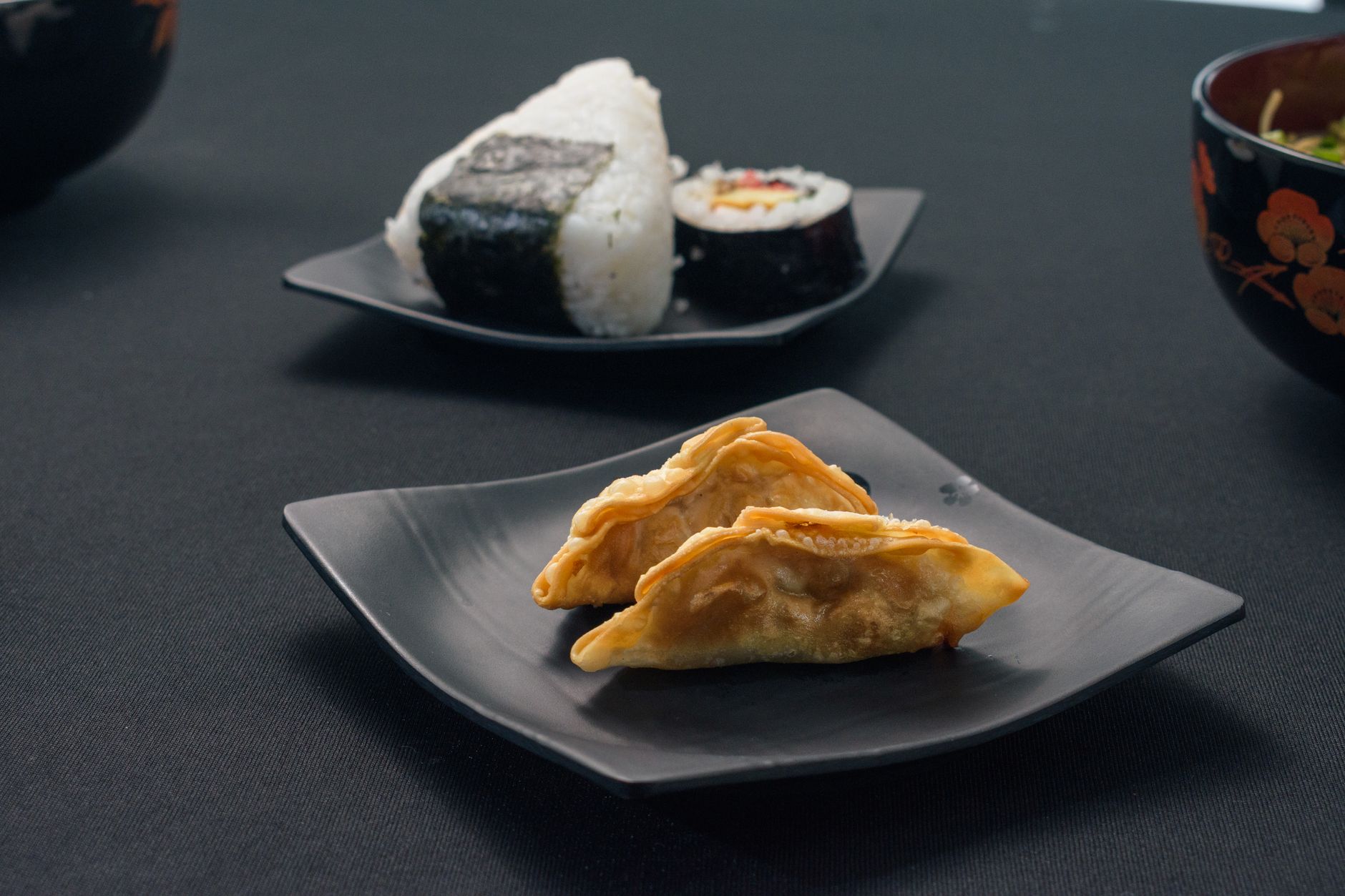 White ceramic plate holds three pieces of sashimi arranged asymmetrically with wasabi, leaving two-thirds of the surface intentionally bare.