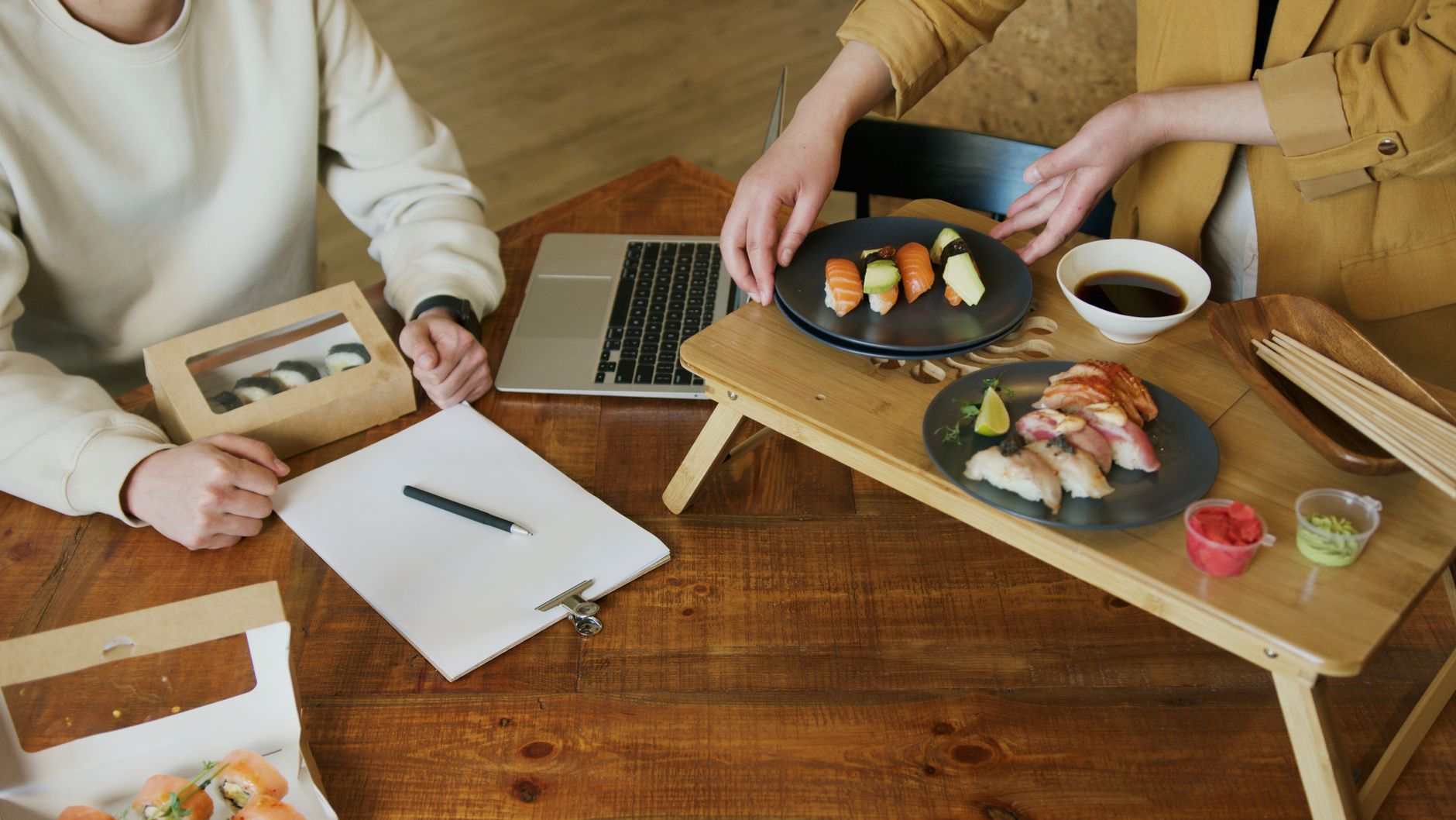 Ceramic bowl with autumn leaf motif holding grilled fish beside smaller dishes on wooden tray in traditional kaiseki setting.