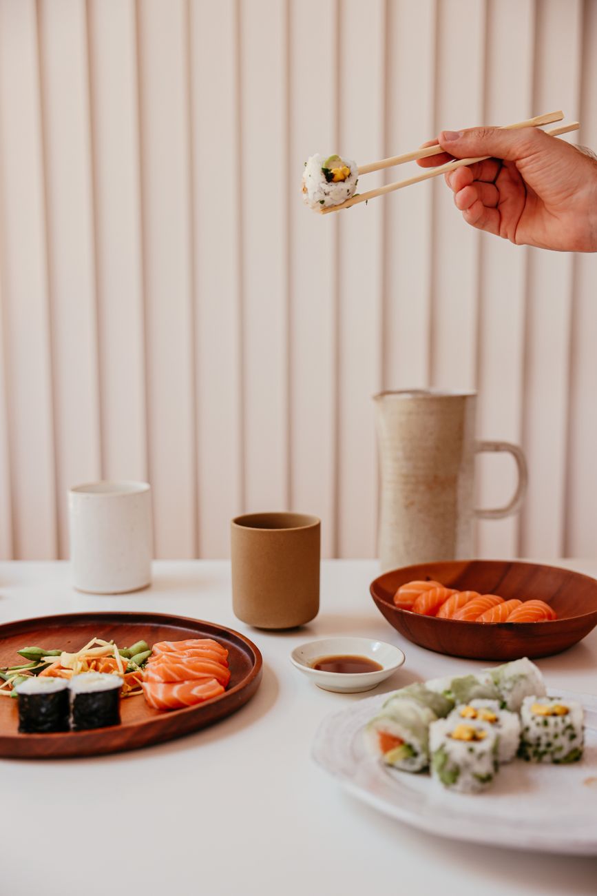Ceramic bowl with autumn leaf motif holding grilled fish beside smaller dishes on wooden tray in traditional kaiseki setting.