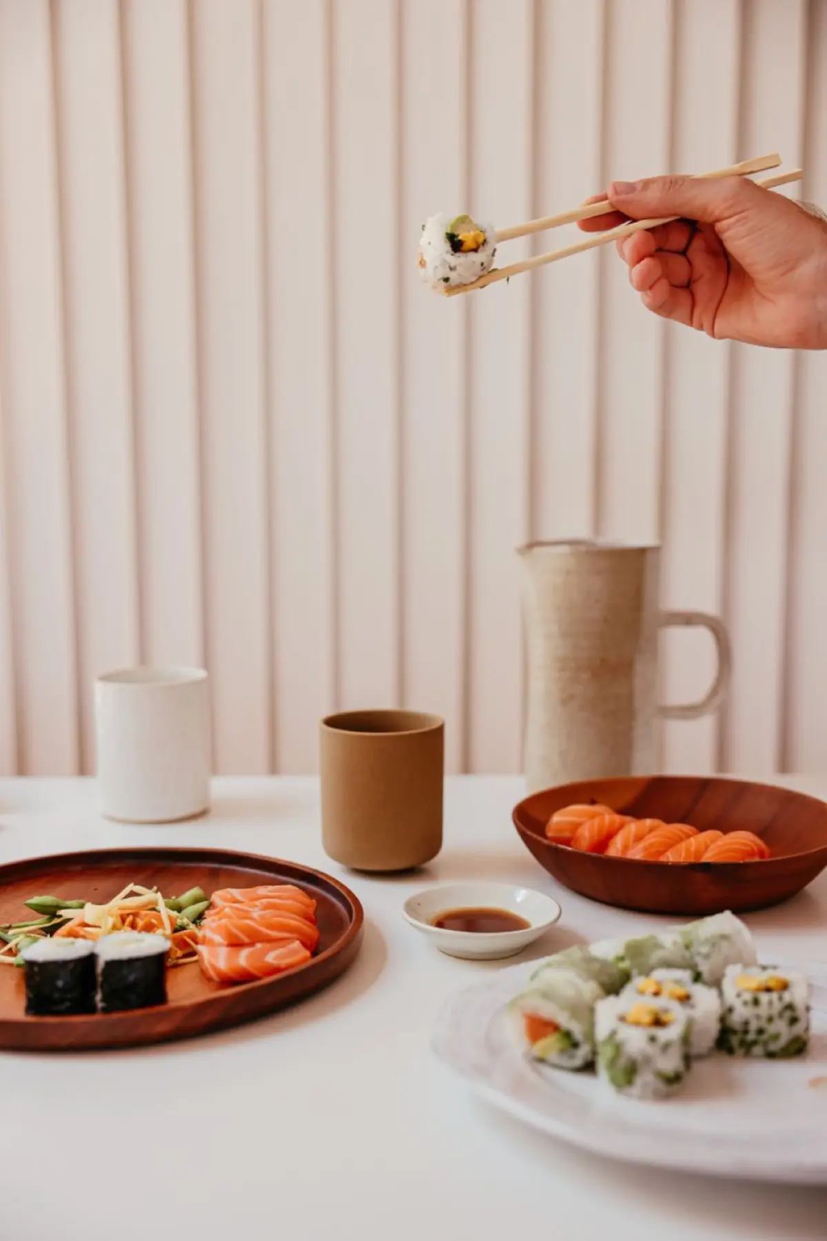 Ceramic bowl with autumn leaf motif holding grilled fish beside smaller dishes on wooden tray in traditional kaiseki setting.