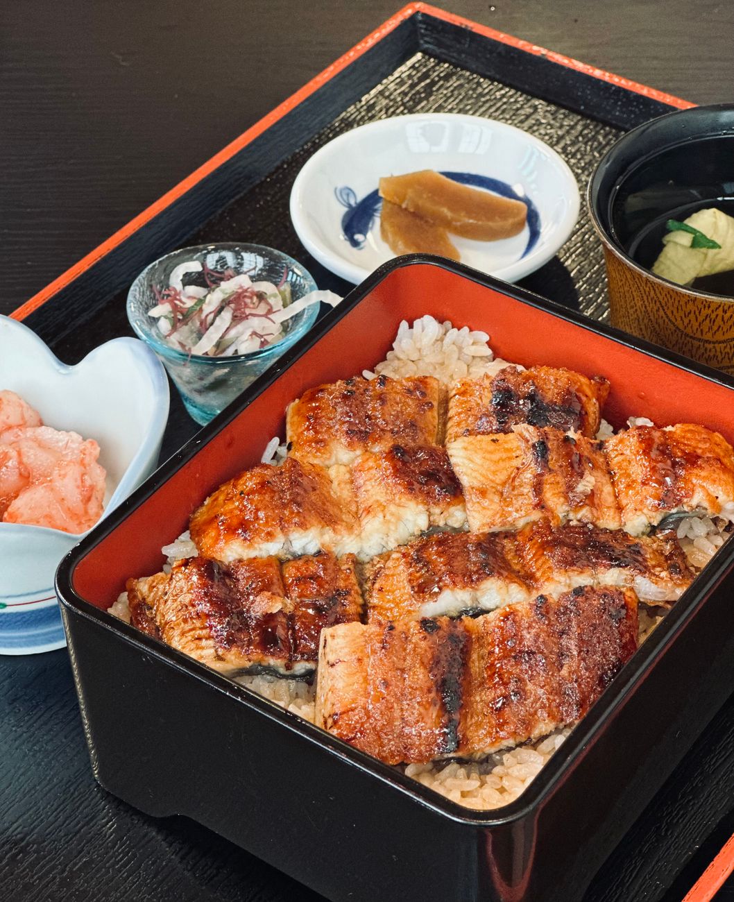 Traditional Japanese meal arrangement showing one soup, three dishes, rice and pickles on lacquered trays in formal samurai dining style.