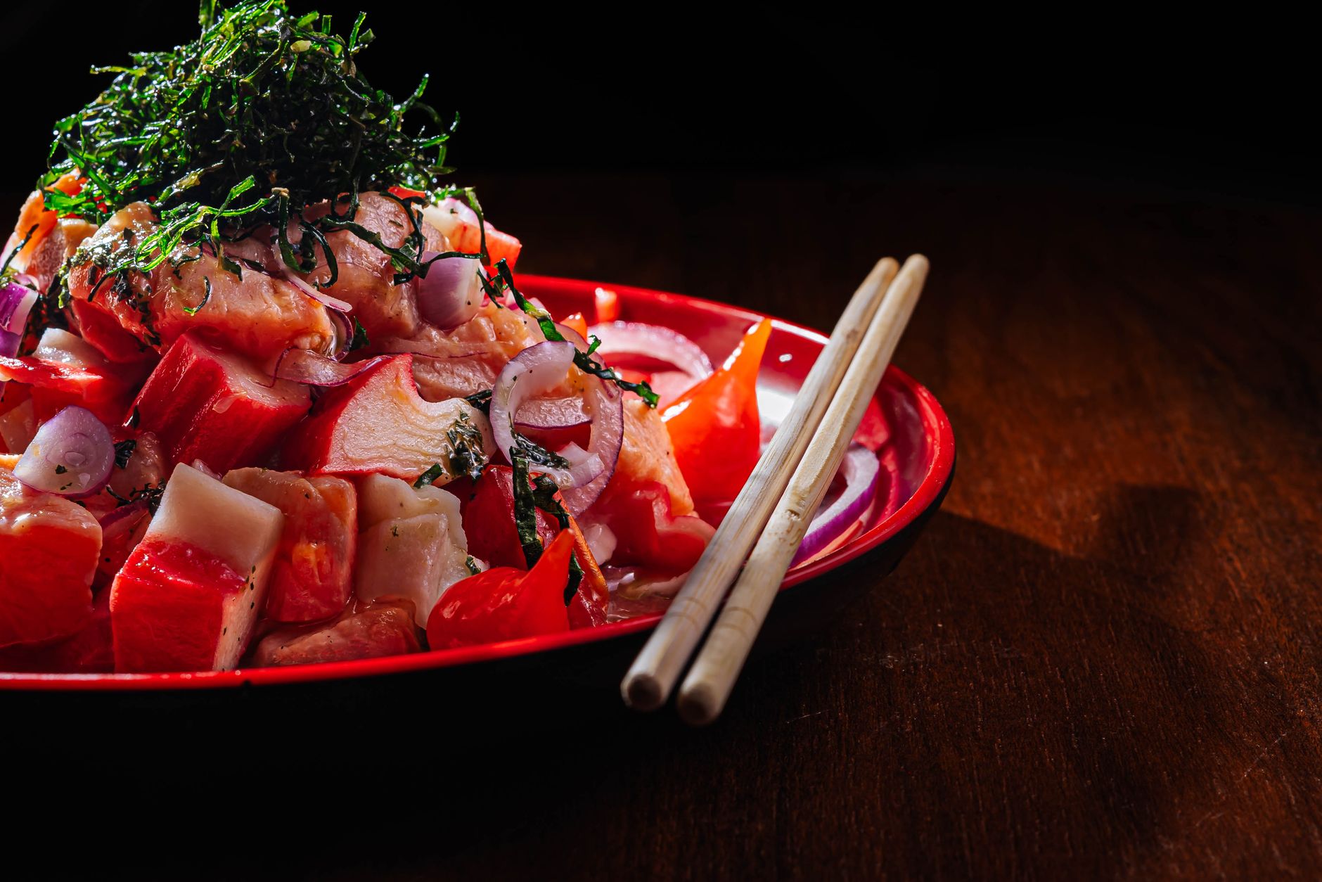 Kaiseki dish arranged with vertical elements showing grilled fish elevated on ceramic stand above seasonal vegetables and garnish.