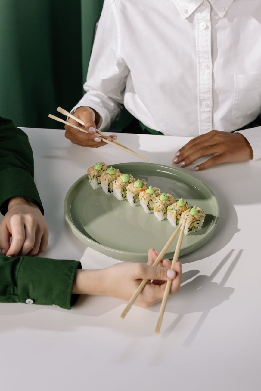 Kaiseki dish arranged with vertical elements showing grilled fish elevated on ceramic stand above seasonal vegetables and garnish.