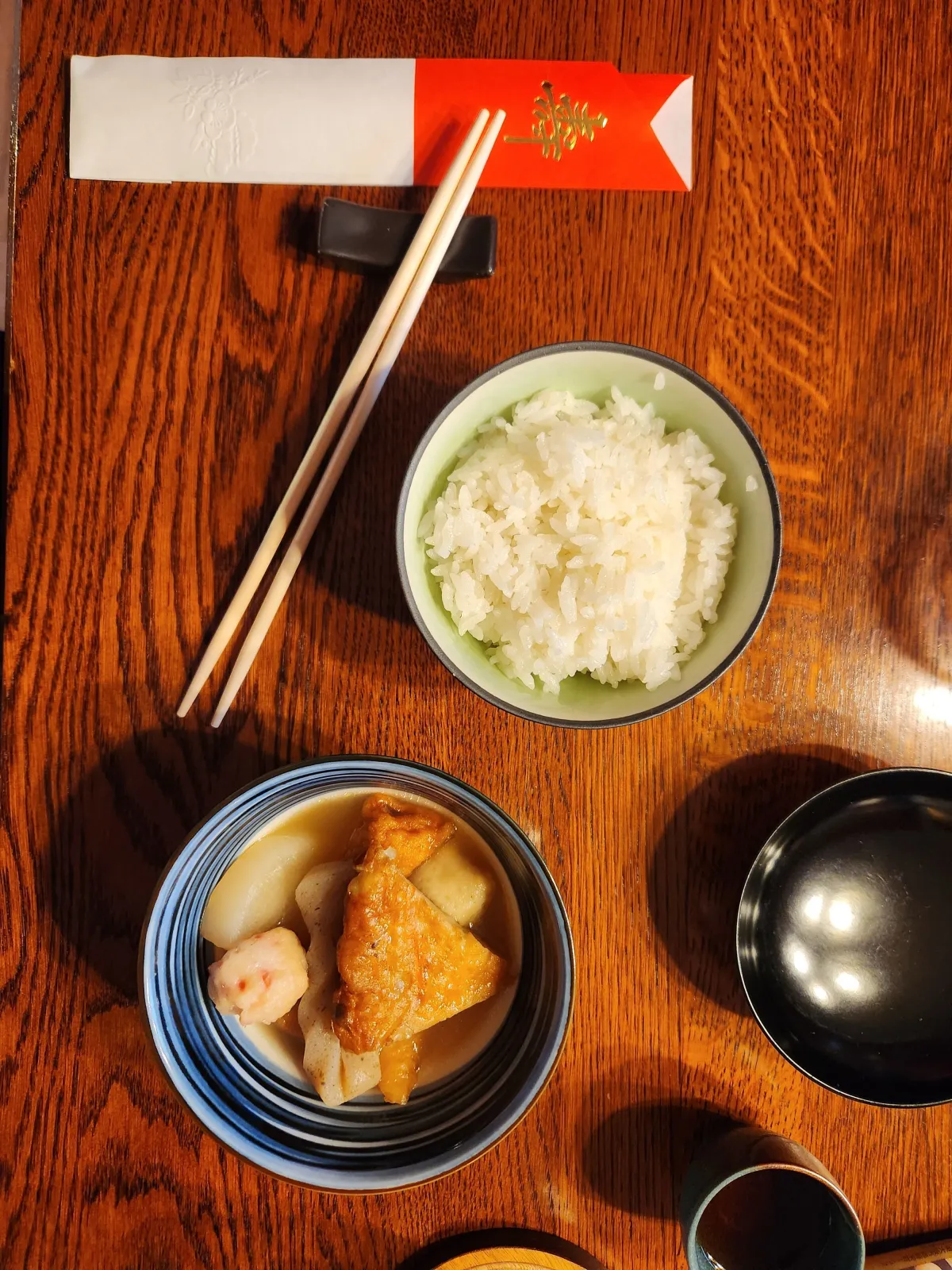 Traditional Japanese meal with rice, pickles, and small dishes arranged on a wooden table, showing minimal portions and no leftover food.