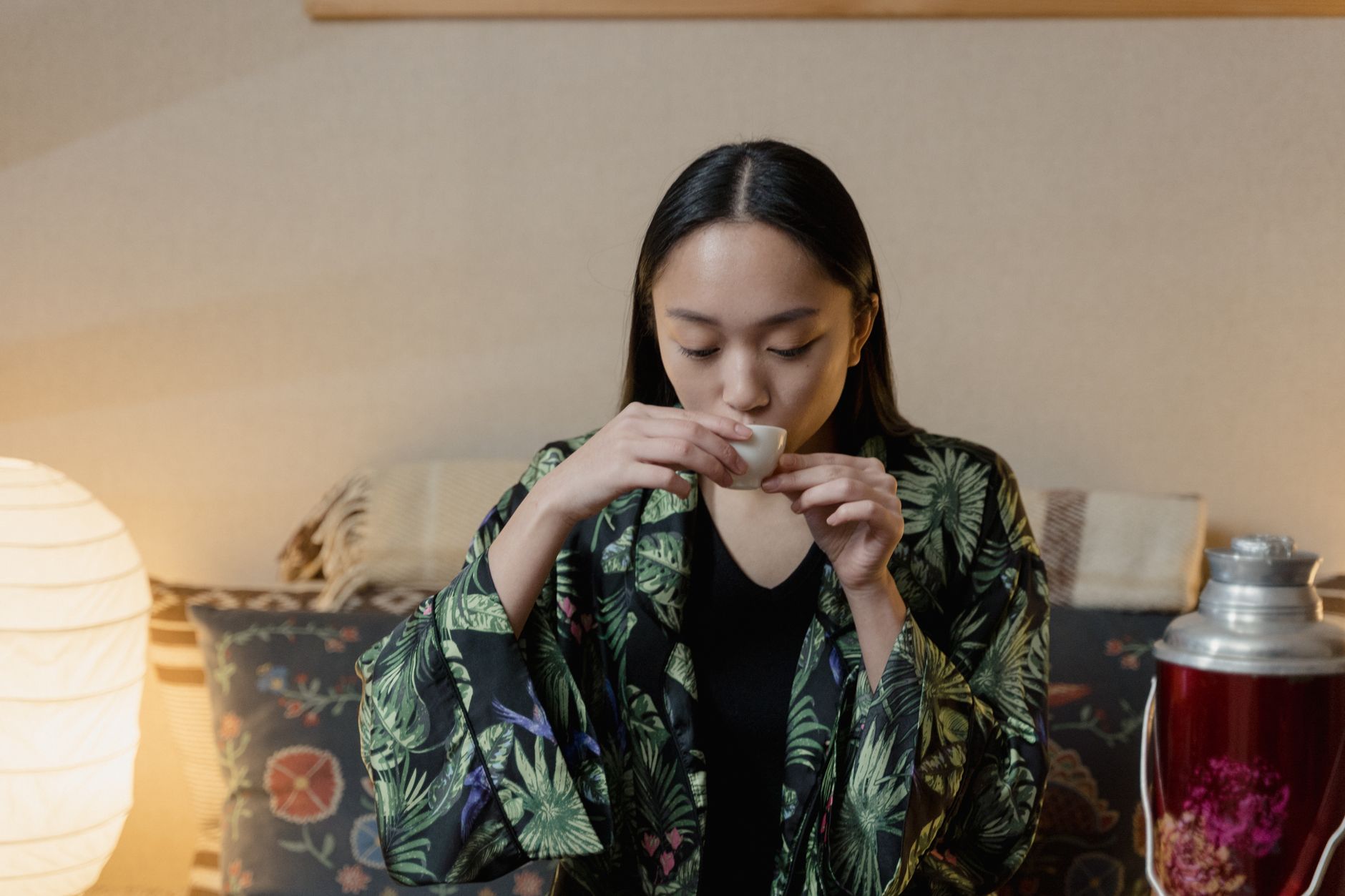Fresh green tea leaves resting in a traditional bamboo steaming basket above gently rising steam in a Japanese tea workshop.