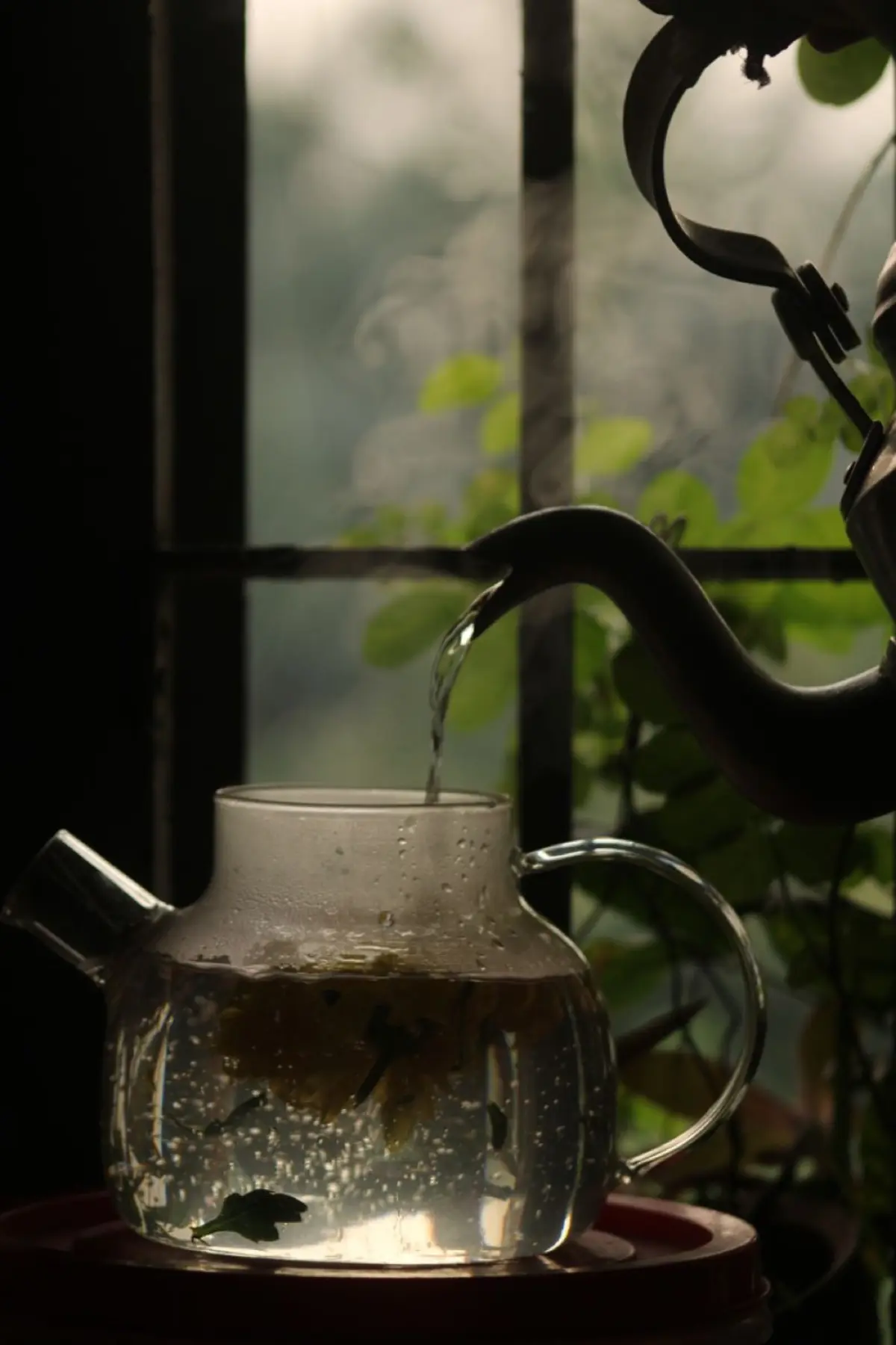 Fresh green tea leaves resting in a traditional bamboo steaming basket above gently rising steam in a Japanese tea workshop.