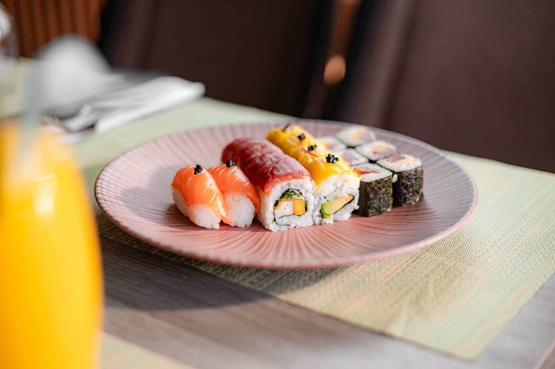 Thinly sliced tuna and salmon arranged in precise diagonal rows with shiso leaves and daikon garnish on white ceramic.