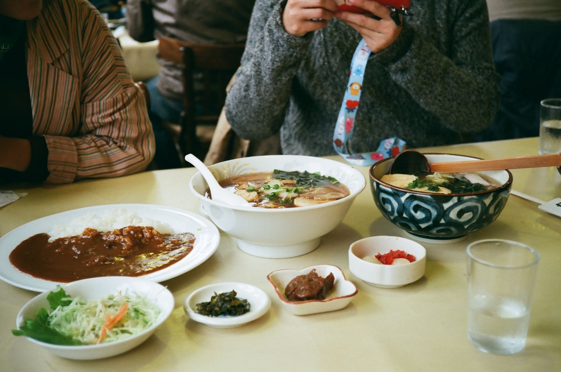 Steaming oyakodon in a ceramic bowl showing tender chicken, soft egg, and scallions over white rice with chopsticks resting beside.