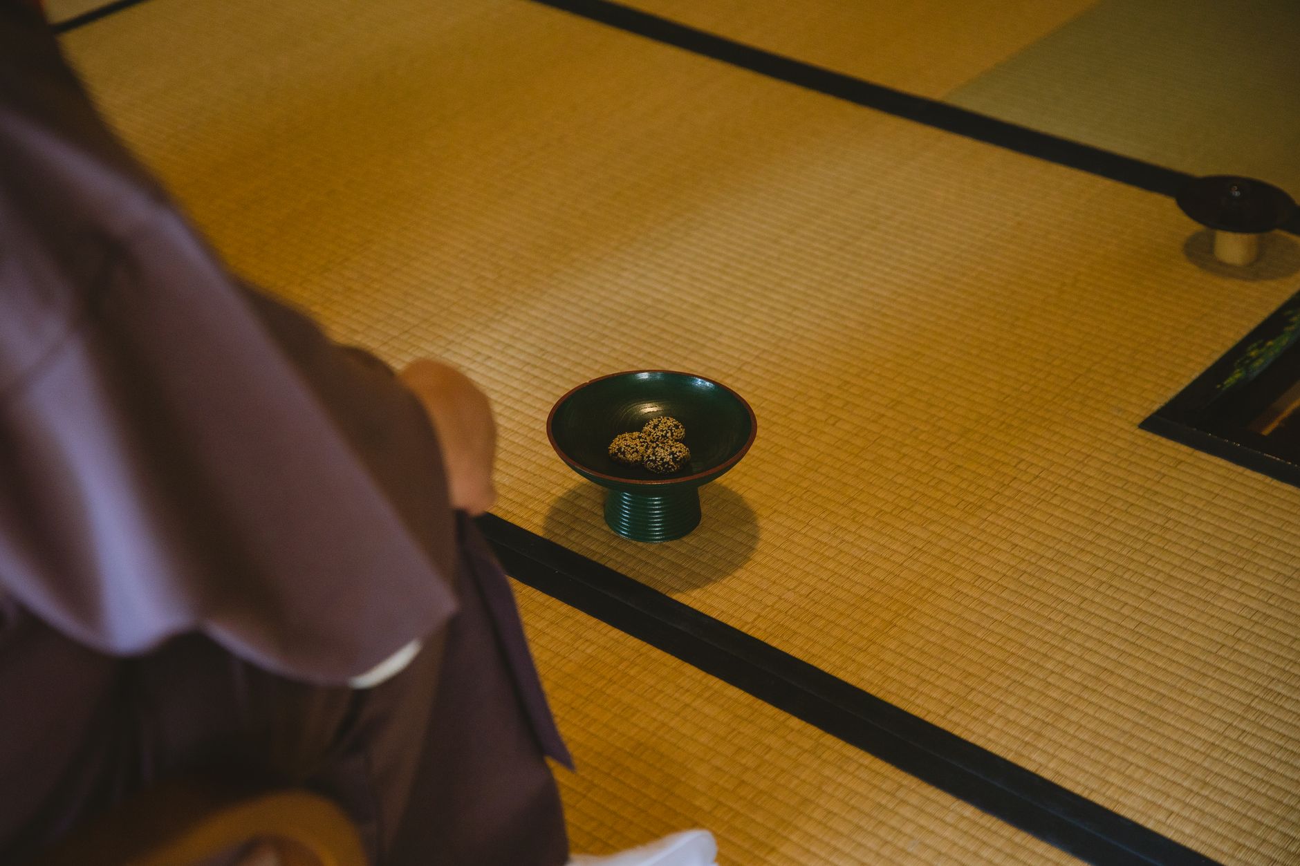 Traditional Japanese dining room with tatami mat flooring, low wooden table, and zabuton cushions arranged for a meal.