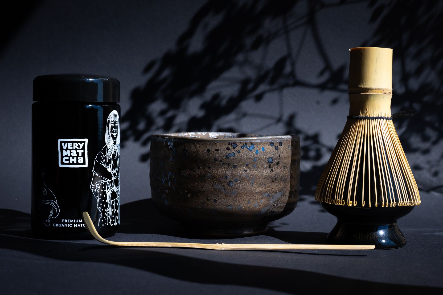 Bamboo chasen tea whisk resting on ceramic holder beside bowl of water after matcha preparation ceremony