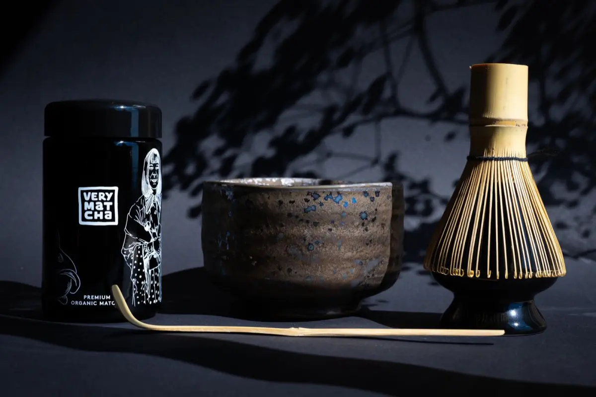 Bamboo chasen tea whisk resting on ceramic holder beside bowl of water after matcha preparation ceremony