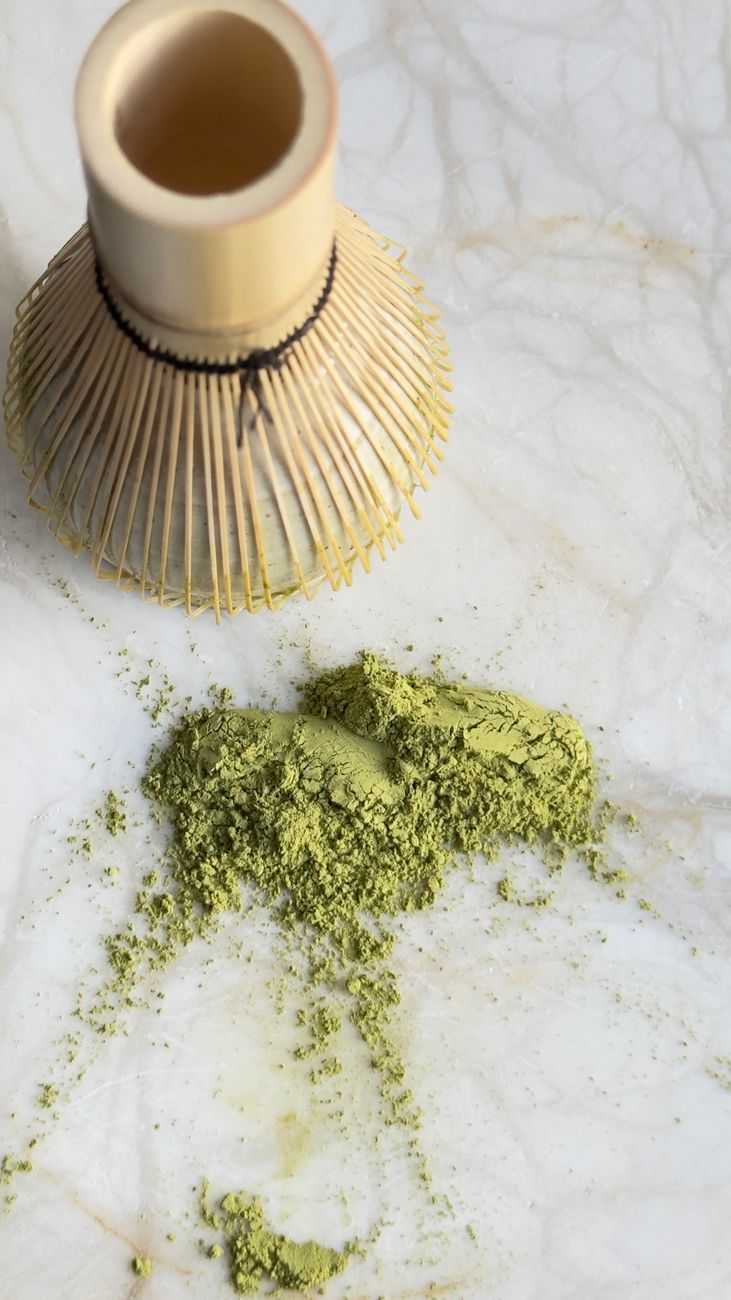 Bamboo chasen tea whisk resting on ceramic holder beside bowl of water after matcha preparation ceremony