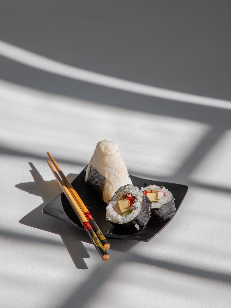 Pair of lacquered wooden chopsticks resting on a ceramic holder beside a traditional Japanese bowl on a table.