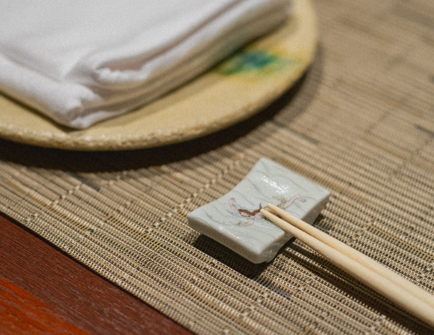 Ancient wooden chopsticks resting on weathered Chinese manuscript beside ceramic bowl, illustrating early utensil design from Tang Dynasty era.