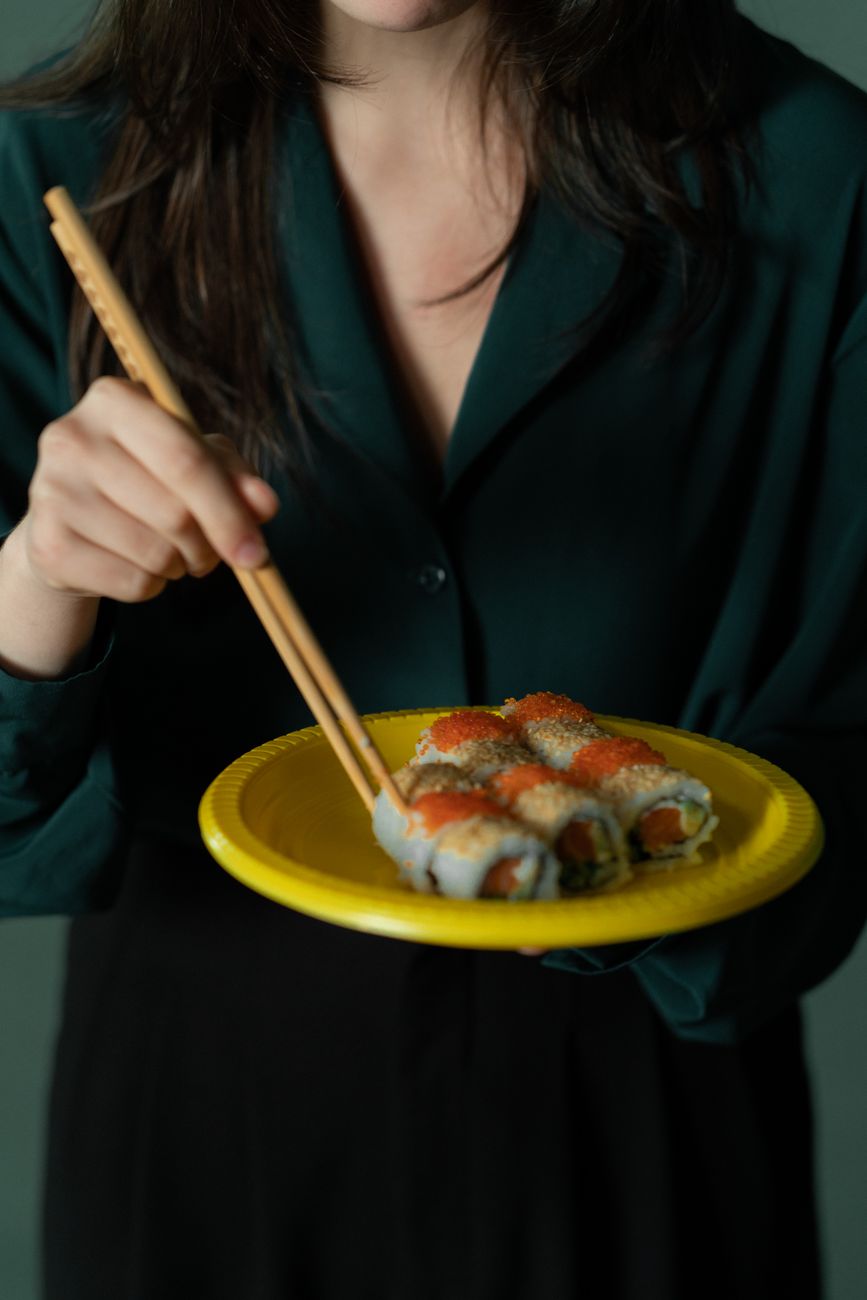 Ancient wooden chopsticks resting on weathered Chinese manuscript beside ceramic bowl, illustrating early utensil design from Tang Dynasty era.