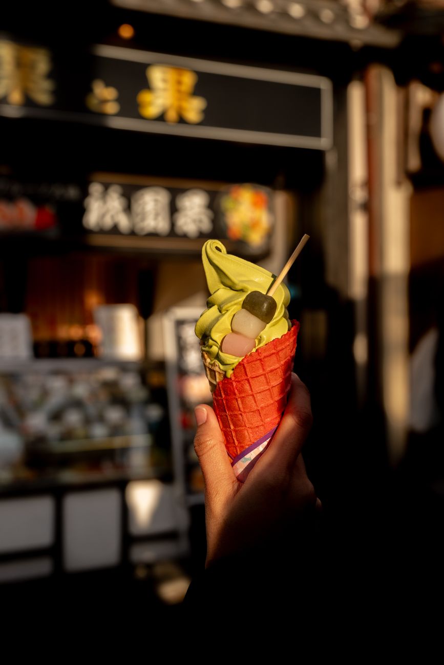 Traditional Japanese matcha tea in a black ceramic bowl beside pink sakura wagashi on a lacquered tray