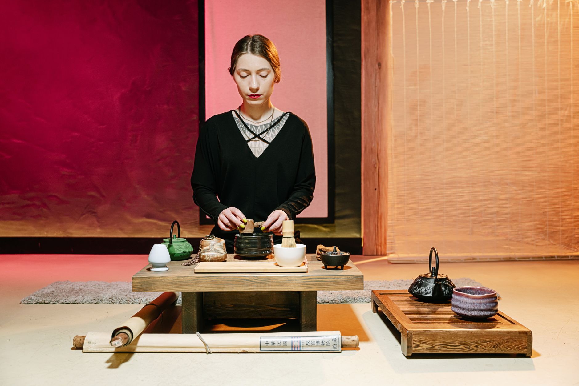 Guest in kimono bowing deeply on tatami mat before entering traditional Japanese tea room with sliding shoji doors.