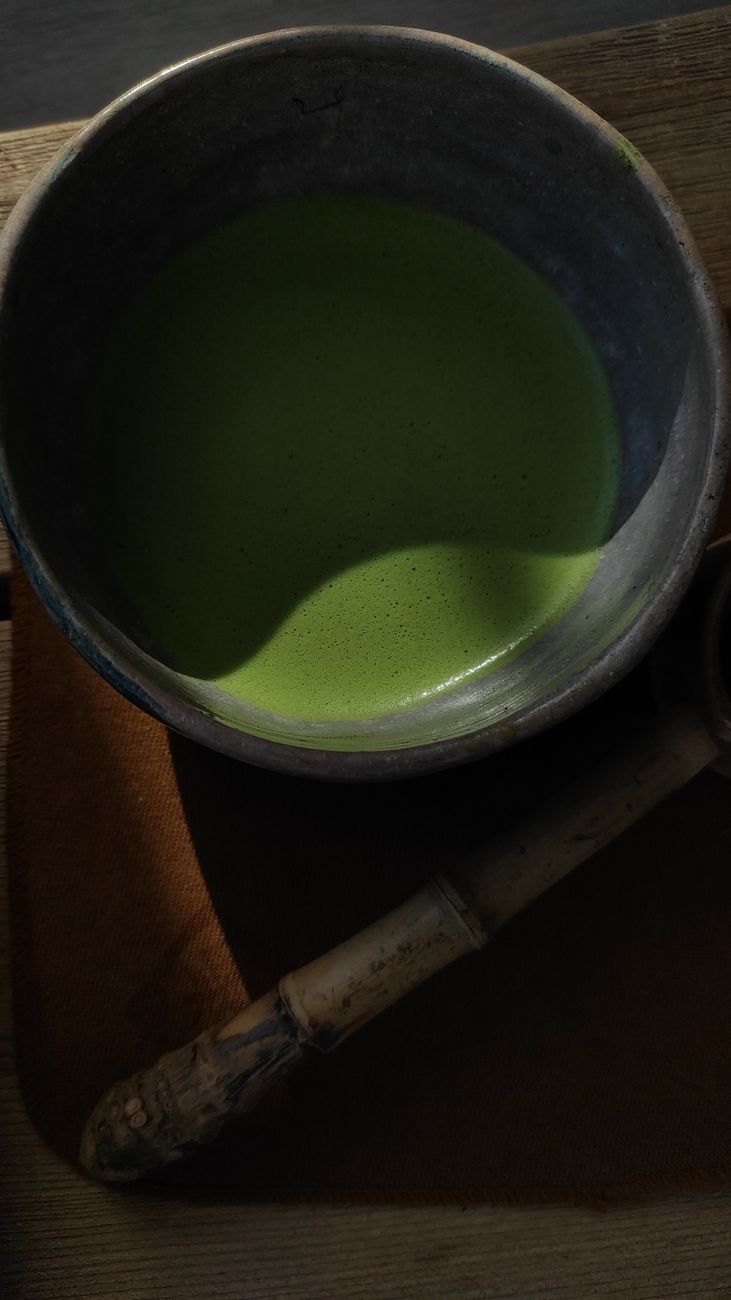 Traditional granite millstones grinding green matcha tea leaves into fine powder in a Japanese tea production facility.