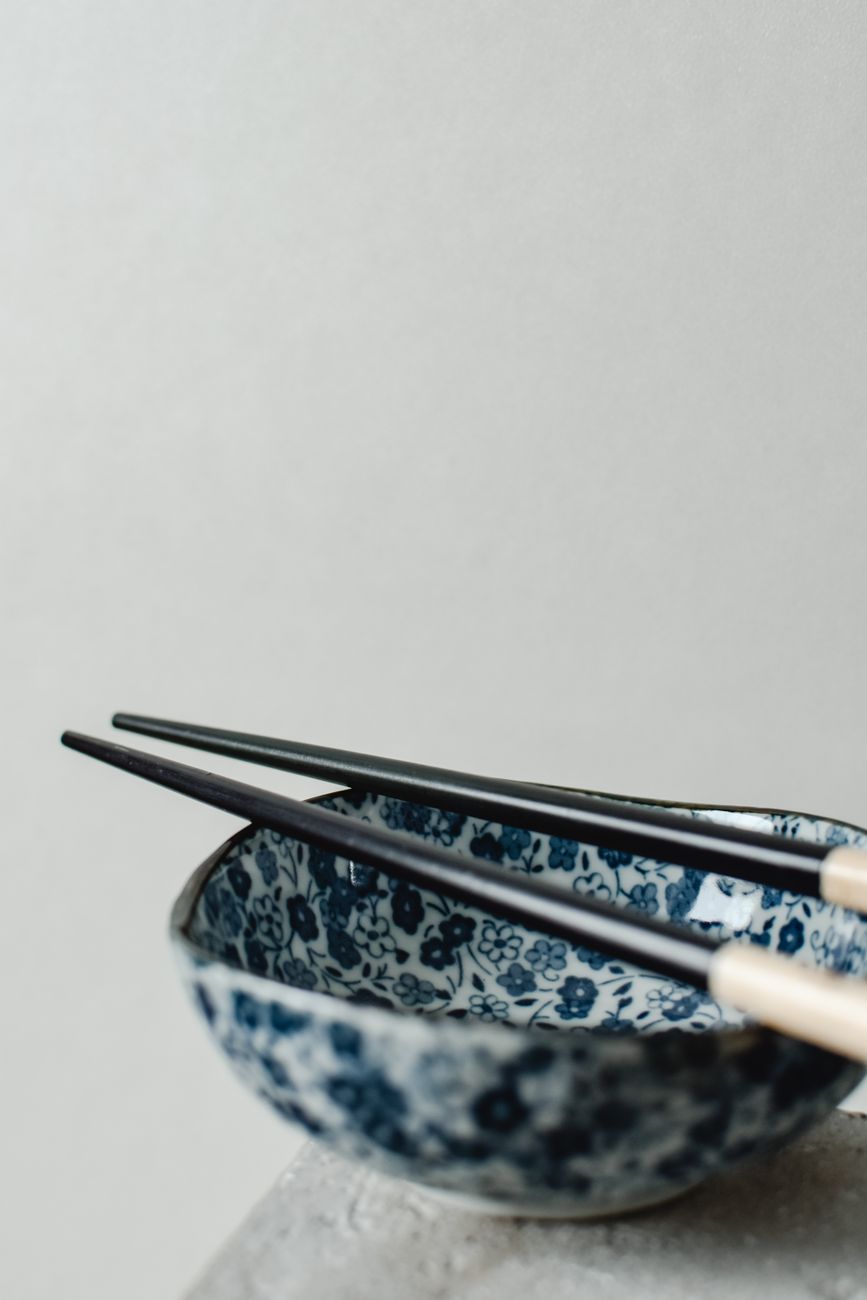 Artisan's hands applying fine gold powder to lacquered chopsticks using a delicate brush in traditional maki-e technique.