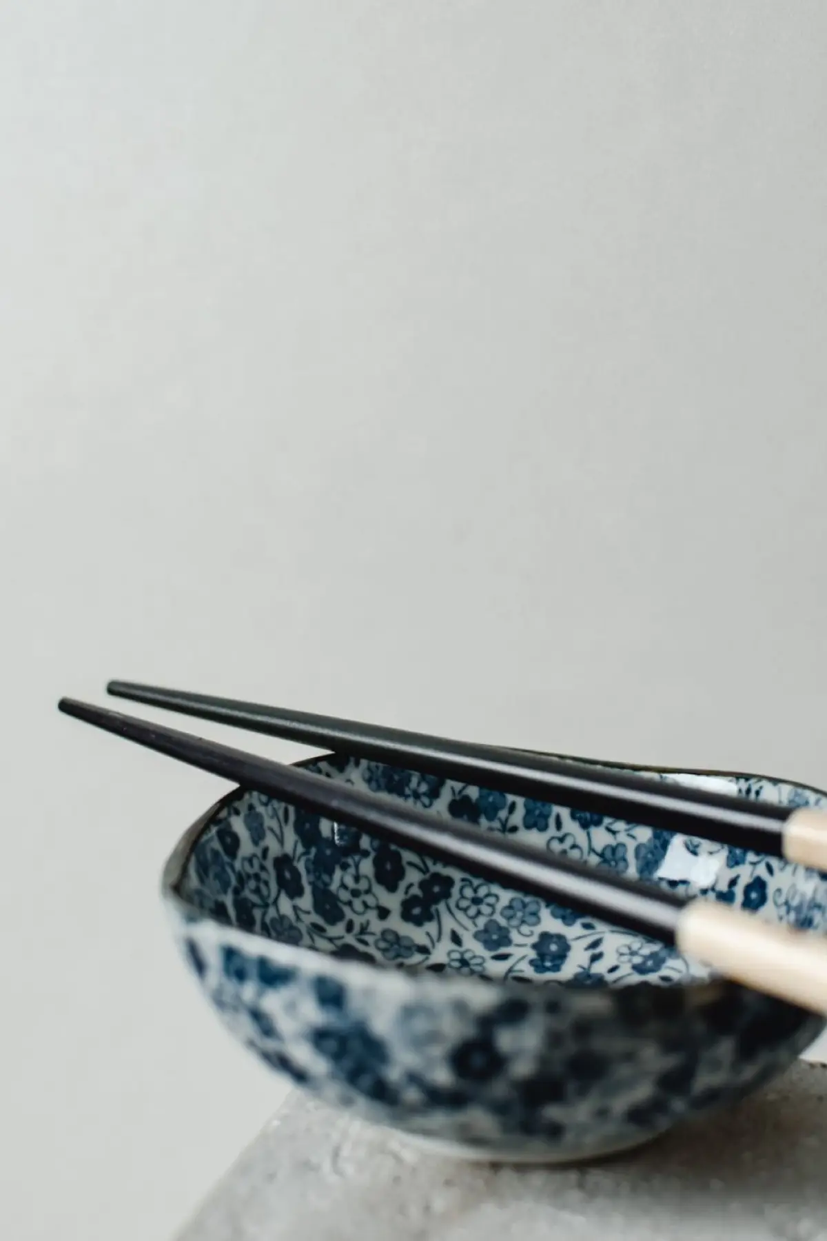 Artisan's hands applying fine gold powder to lacquered chopsticks using a delicate brush in traditional maki-e technique.