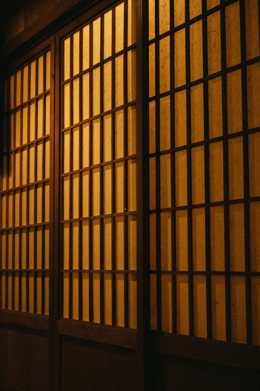 Shoji screen with traditional kumiko wooden lattice and translucent washi paper filtering soft natural daylight