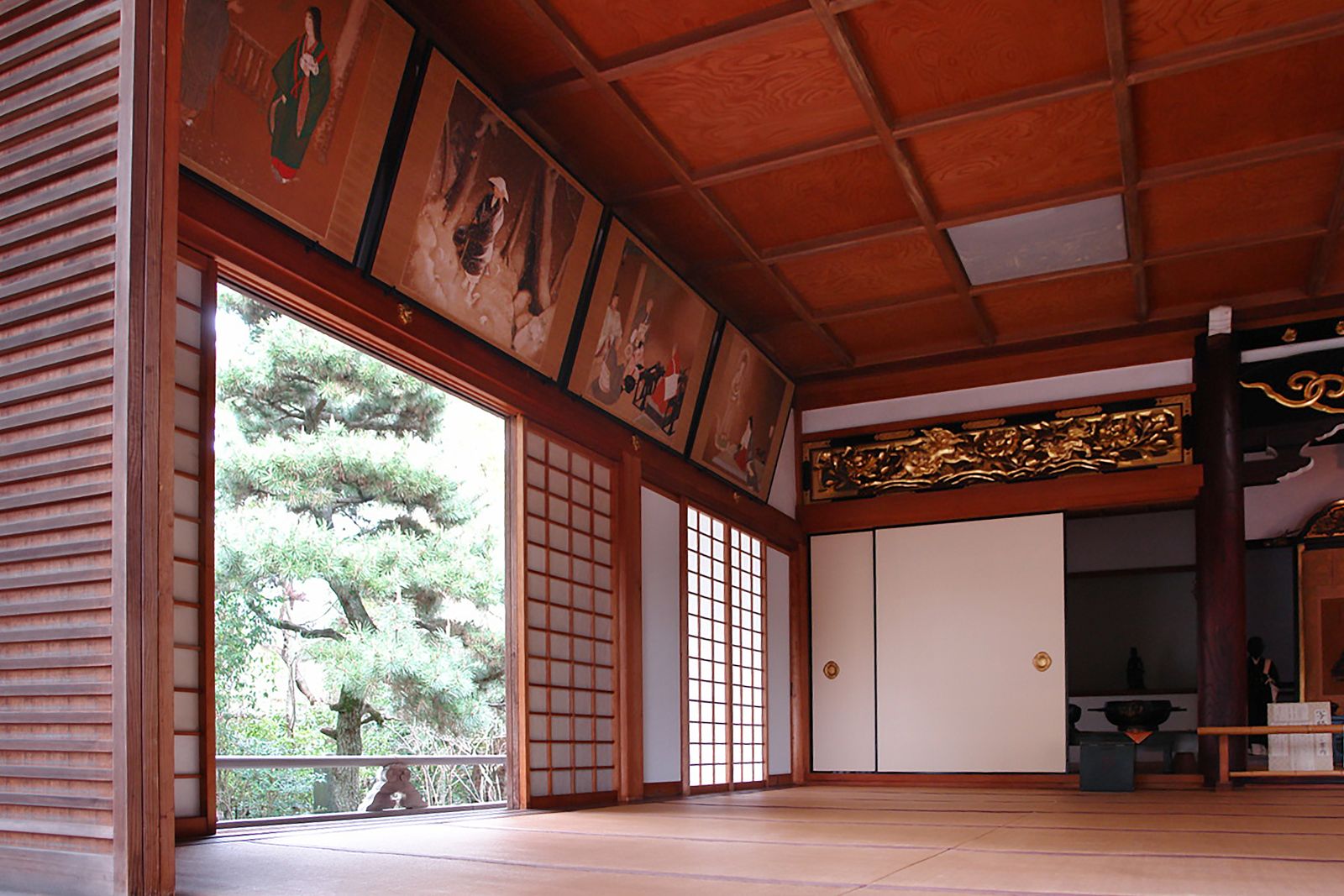 Intricately carved wooden ranma transom panel above shoji doors in a traditional Japanese interior, casting delicate shadows.