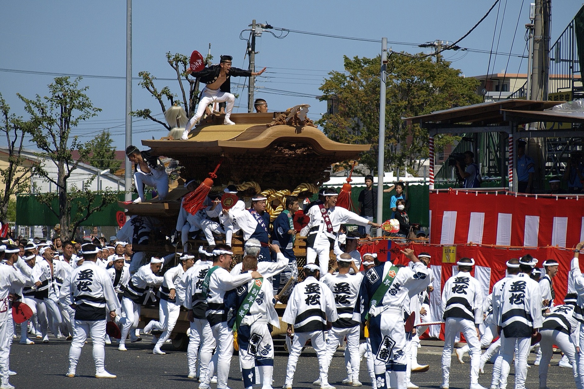Massive wooden danjiri float tilting sharply as it rounds a corner at speed during Osaka's Kishiwada Danjiri Matsuri