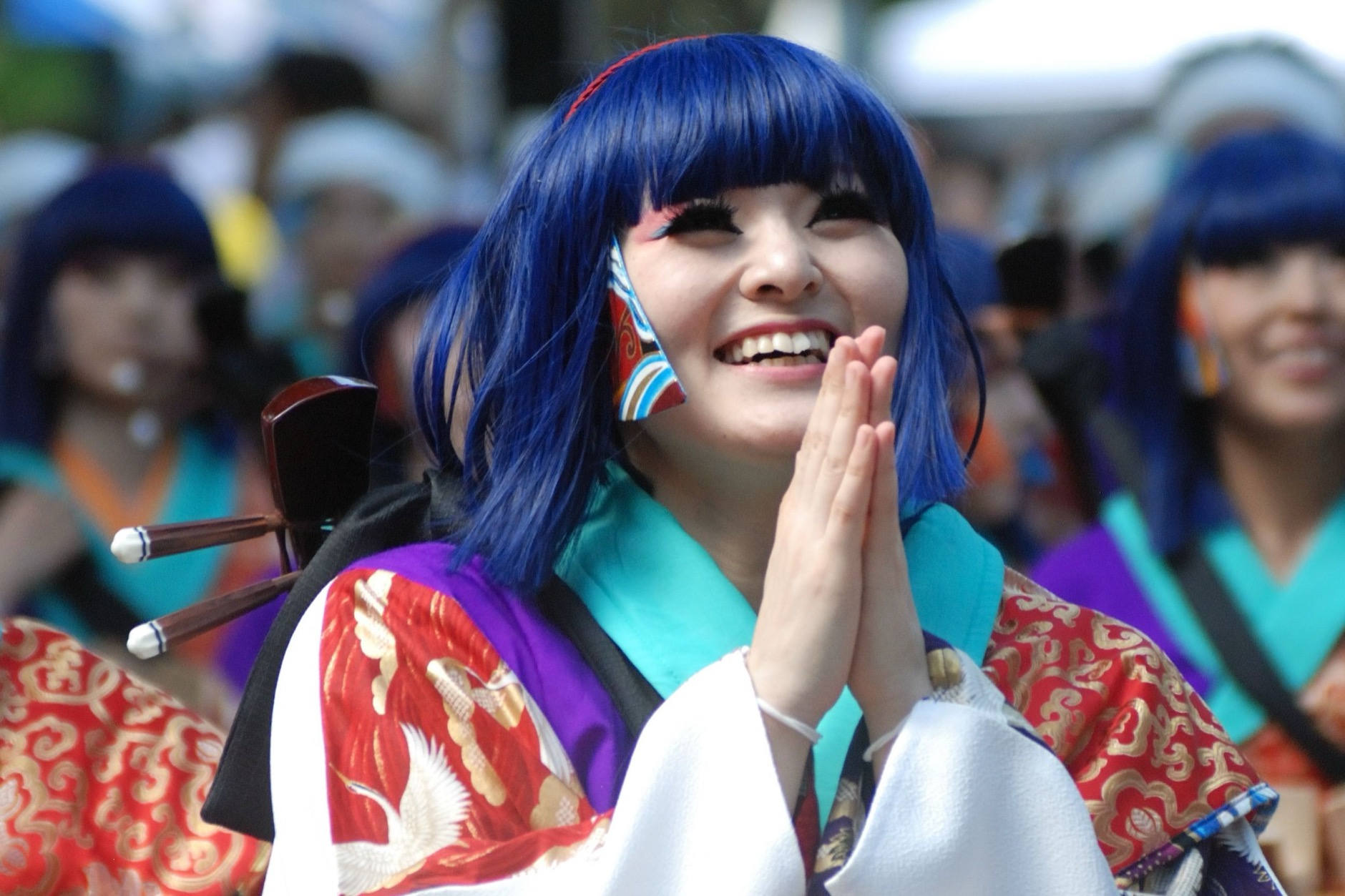 Yosakoi dancers in vibrant costumes performing with naruko wooden clappers during a summer street festival in Japan.