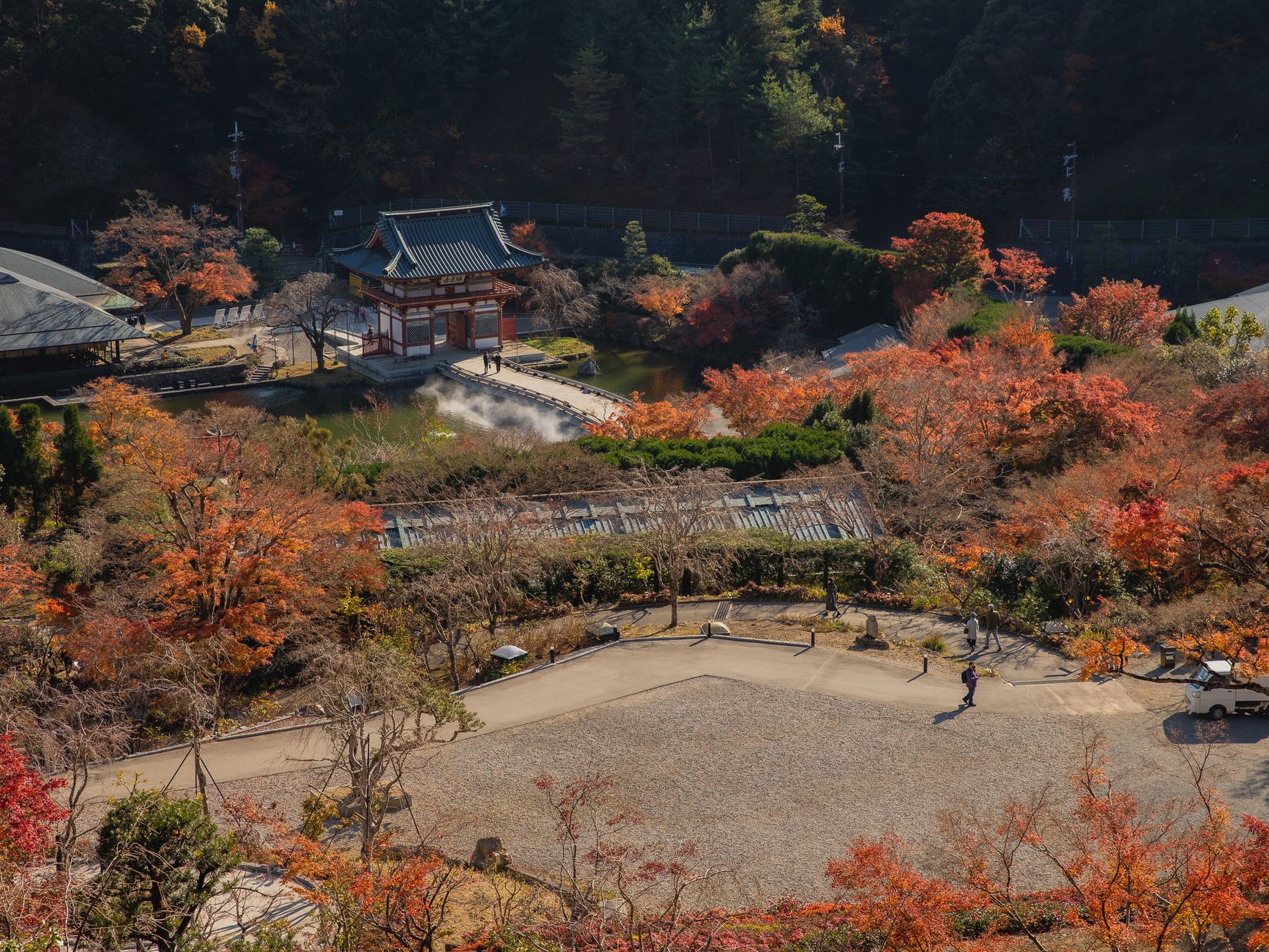 Traditional Japanese garden with stone path and pruned pine framing a distant mountain view beyond the garden wall