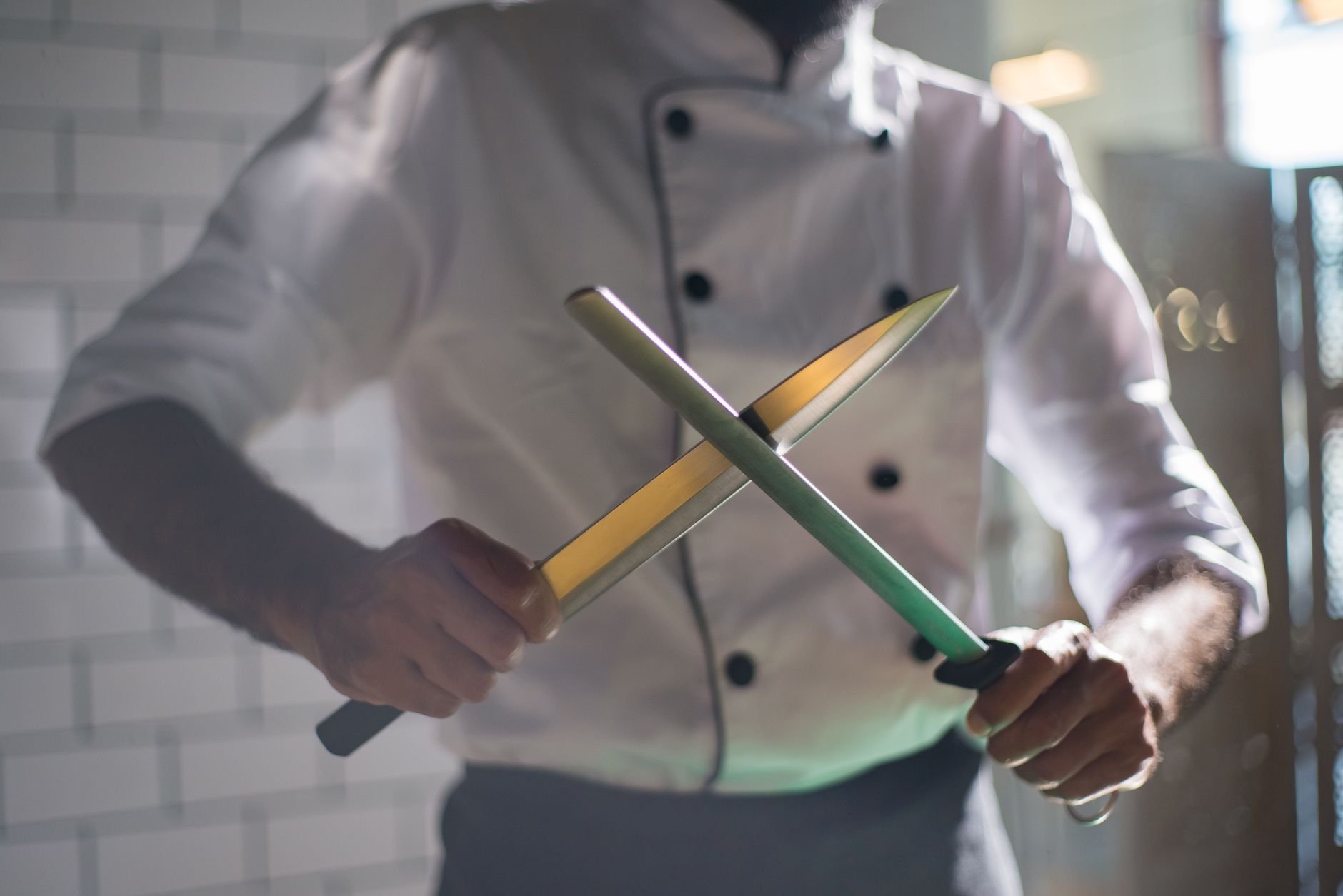 Close-up of a Japanese yanagiba knife with single-bevel edge resting on a wooden cutting board beside fresh fish